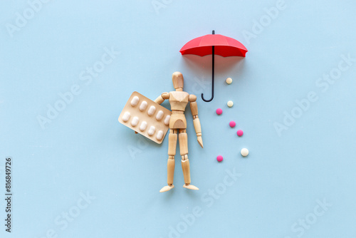 Medical insurance concept - wooden dummy man with umbrella