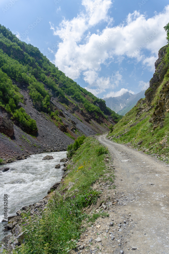 Stream of the Terek River and gravel road at the bottom of the gorge Stream of the Terek River and gravel road at the bottom of the gorge