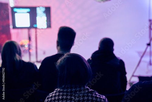 An audience with people in the background is a screen with a presentation. A rear view of unfamiliar participants in the audience. Scientific conference, training. High quality photo