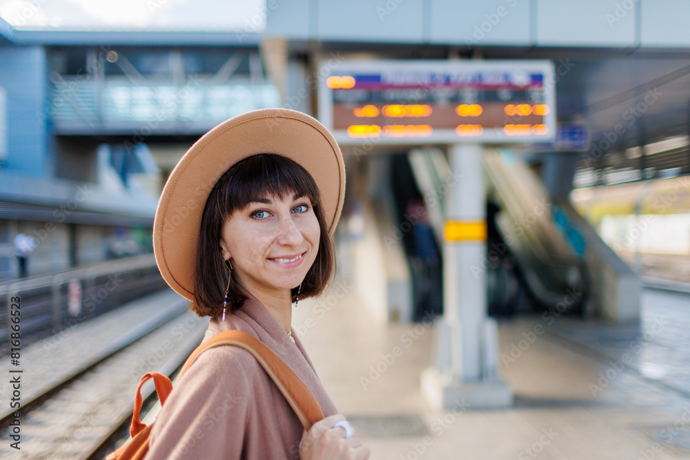 young girl at the railway station. girl with a backpack. A young woman in a coat and hat is standing on the station platform. adventures and travel. young girl at the railway station. girl with a backpack. A young woman in a coat and hat is standing on the station platform. adventures and travel.