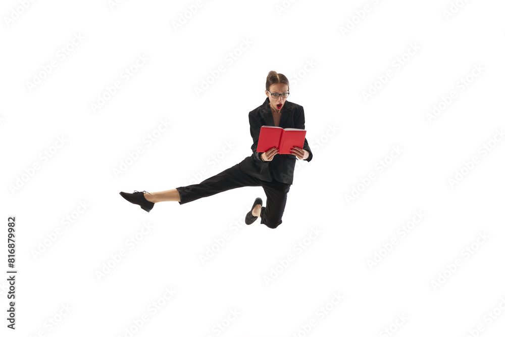 Emotional businesswoman in motion, in mid-air pose jumping with shocked face and looking in book, notes isolated on white background. Concept of business, office life, professional learning, progress