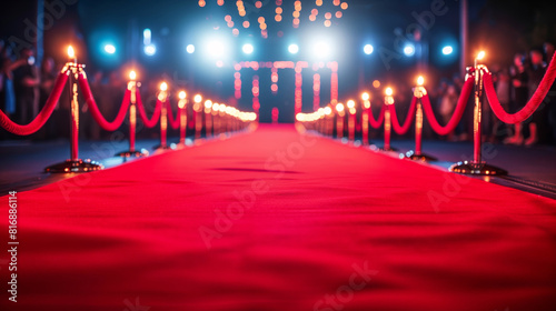 A glamorous red carpet event featuring a brightly lit pathway lined with red ropes and stanchions, flanked by spotlights and an elegant ambiance, perfect for premieres or award ceremonies. photo