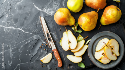 Top view of fresh pears on a dark textured surface, including whole pears and sliced pieces on a black cutting board next to a kitchen knife. photo