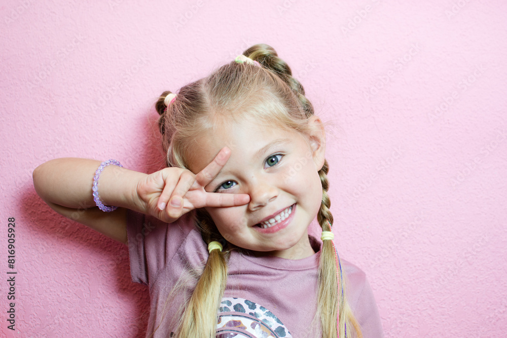 Portrait of a cute Caucasian blonde little girl showing a peace sign. good mood concept Portrait of a cute Caucasian blonde little girl showing a peace sign. good mood concept