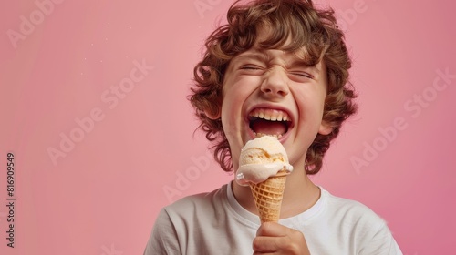 Child with painful expression eating ice cream - A child looks agonized as he eats from a cone of vanilla ice cream, his face contorted in pain on pink backdrop photo