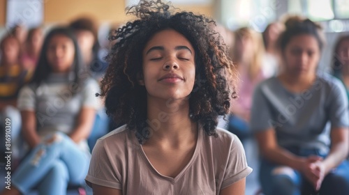 A young woman is seen meditating in front of a group of people. photo