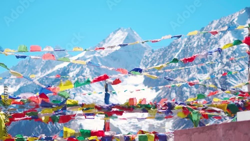 Slow motion shot of prayer flags waving in the wind in front of the snow covered Himalayan mountains at Kunzum Pass on the way to Kaza from Manali in Himachal Pradesh, India. Prayer flags at Kunzum. 