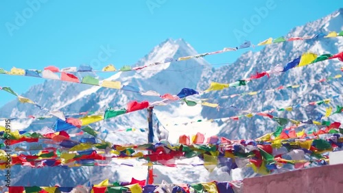 Slow motion shot of prayer flags waving in the wind in front of the snow covered Himalayan mountains at Kunzum Pass on the way to Kaza from Manali in Himachal Pradesh, India. Prayer flags at Kunzum.  photo