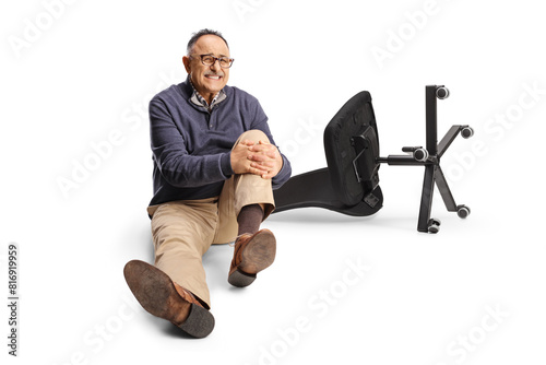 Mature man falling froma chair holding his painful knee and sitting on the ground photo