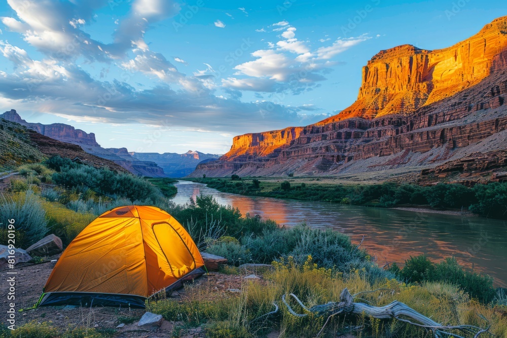 Camping tent by the river at dusk with towering canyon walls in the background. Adventure and travel concept. Scenic landscape photography for travel guide, poster, and environmental awareness.