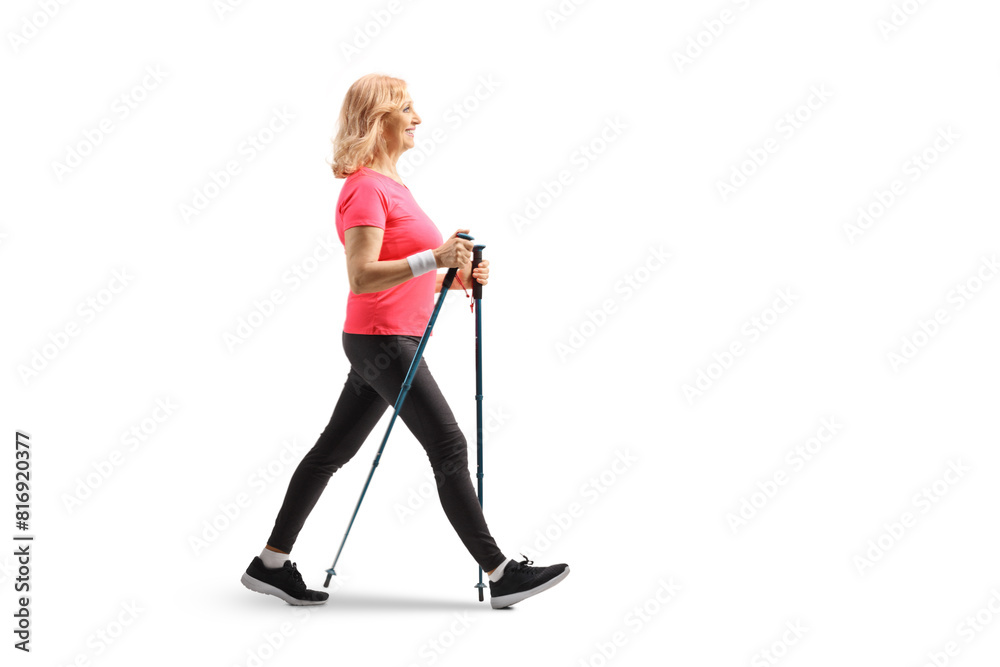 Full length profile shot of a middle aged woman walking with trekking poles