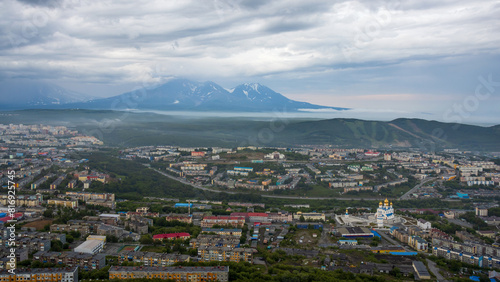 Beautiful cityscape. Top view of the cathedral, buildings and streets. Volcanoes in the distance. Overcast weather. Low clouds. City of Petropavlovsk-Kamchatsky, Kamchatka Territory, Russian Far East.
