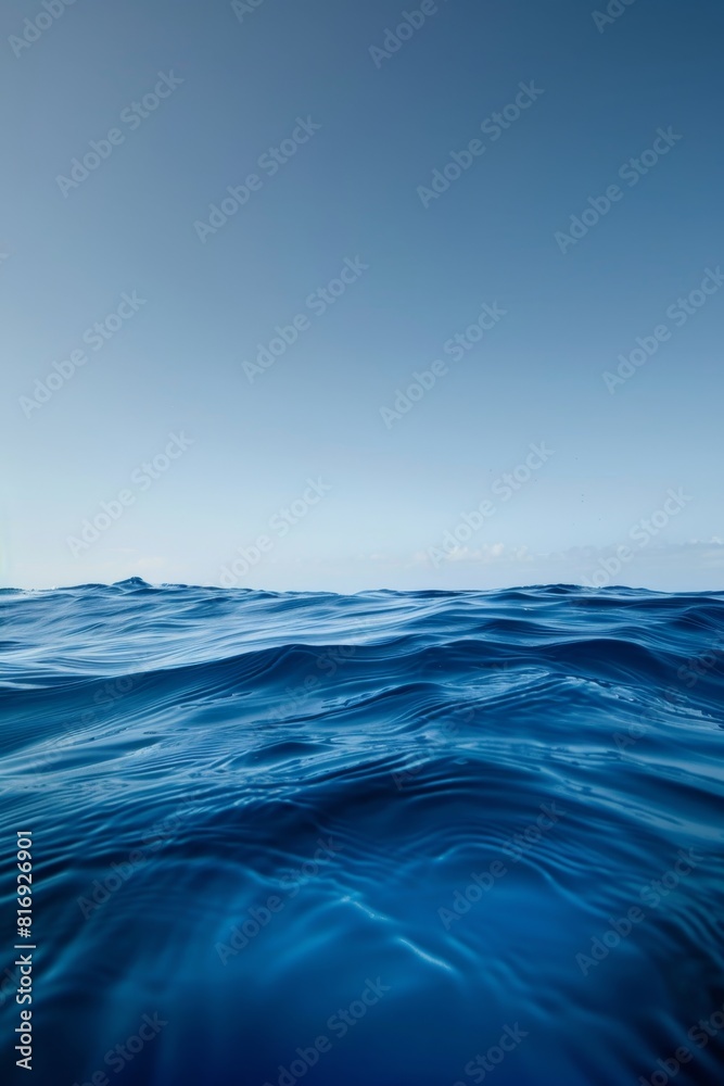 Fototapeta premium Clear blue ocean under a bright sky - Pristine view of the clear blue ocean gently undulating under a bright and sunny sky, evoking a sense of calm and clarity