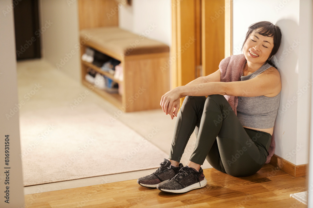 A tired japanese sportswoman sitting on the floor at home and relaxing with music. A tired japanese sportswoman sitting on the floor at home and relaxing with music.