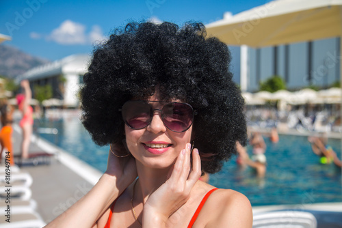 Summer day the pool: smiling woman with black curly hair.
