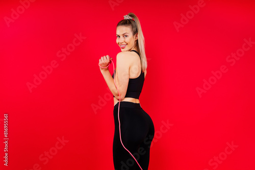 Blond woman with jump rope in studio, yellow red and dark background