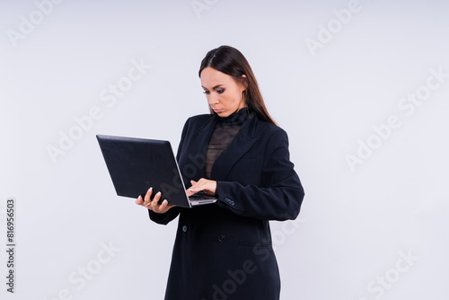 Attractive woman wearing business suit with computer angry facial expression holding a hammer