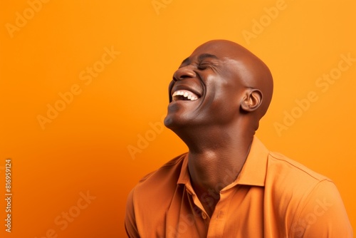 Portrait of a grinning afro-american man in his 40s laughing over soft orange background