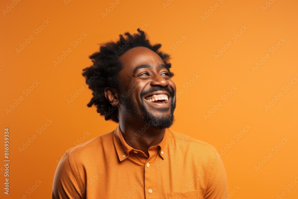 Portrait of a grinning afro-american man in his 40s laughing in front of soft orange background Portrait of a grinning afro-american man in his 40s laughing in front of soft orange background