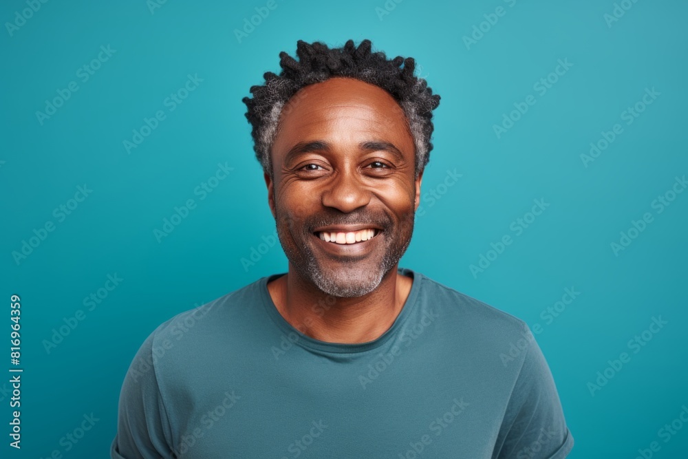 Portrait of a grinning afro-american man in his 40s smiling at the camera isolated in soft teal background Portrait of a grinning afro-american man in his 40s smiling at the camera isolated in soft teal background