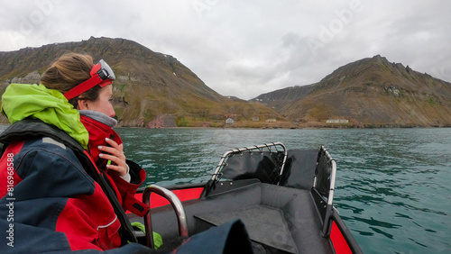 Traveler woman in an Arctic rib boat safari in Longyearbyen, Svalbard. Equiped tourist exploring Spitsbergen fjords and Arctic ocean adventure