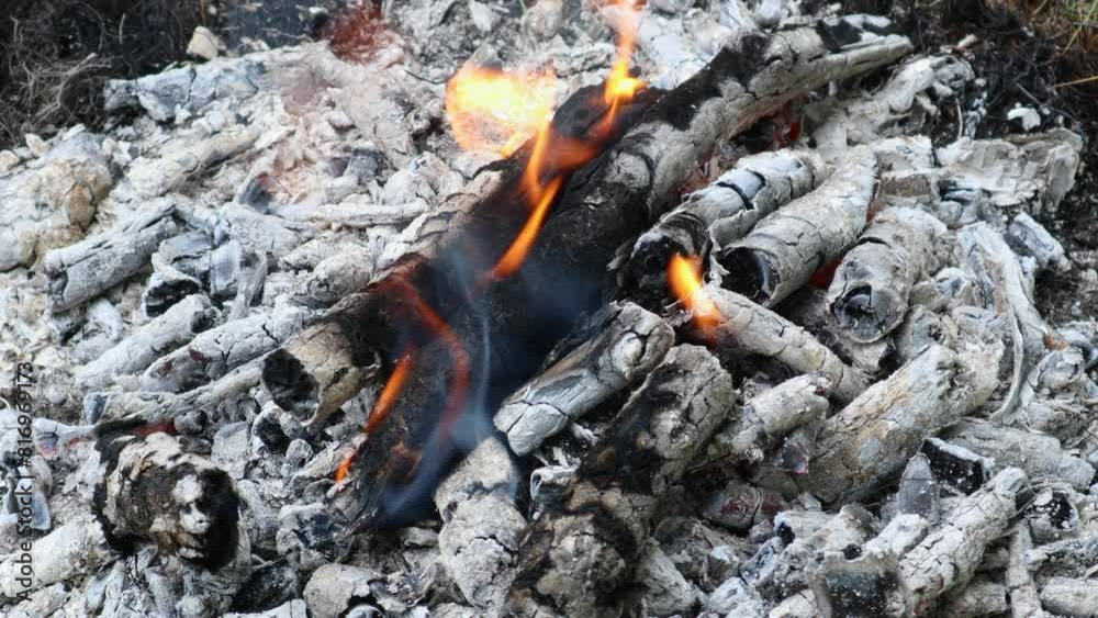 Close-up of a fading campfire with glowing embers and flickering flames Close-up of a fading campfire with glowing embers and flickering flames