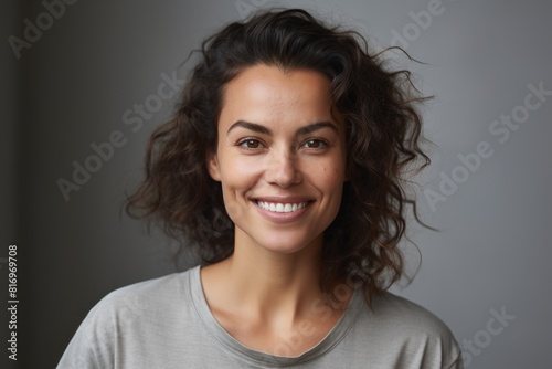 Portrait of a glad woman in her 30s smiling at the camera over soft gray background © Markus Schröder