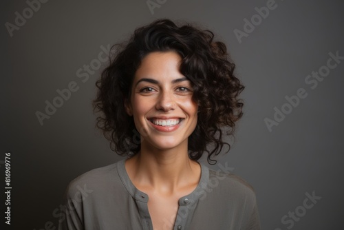 Portrait of a glad woman in her 30s smiling at the camera isolated on soft gray background