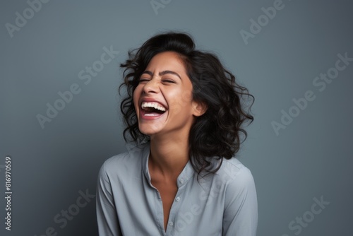 Portrait of a cheerful indian woman in her 30s laughing isolated on soft gray background