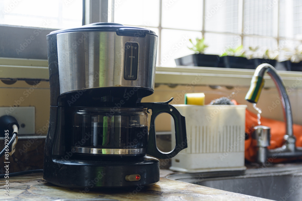 A Coffee Maker sits on a counter next to a sink