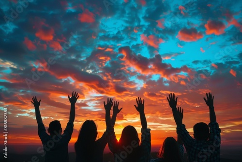 A Group Of People With Their Arms Up In The Air Praising and Praying Looking At The Sunset