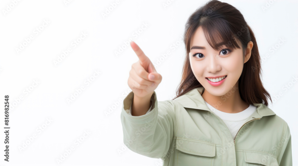 A young woman in a green jacket is pointing at something off-camera with a smile on her face. A young woman in a green jacket is pointing at something off-camera with a smile on her face.