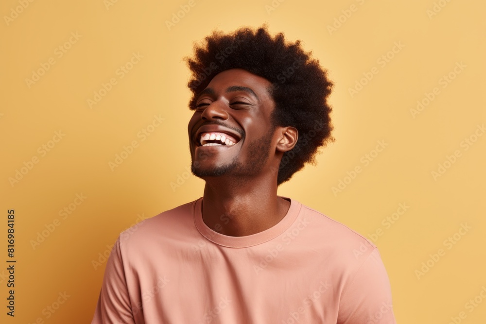 Portrait of a blissful afro-american man in his 20s laughing in front of soft brown background Portrait of a blissful afro-american man in his 20s laughing in front of soft brown background