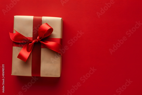 A detailed shot of a beautifully wrapped gift box with a ribbon on a solid red background 