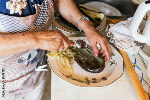 Elderly woman preparing eggplant in kitchen photo