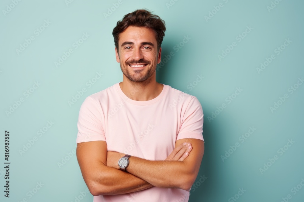 Portrait of a grinning man in his 30s with arms crossed on pastel or soft colors background Portrait of a grinning man in his 30s with arms crossed on pastel or soft colors background