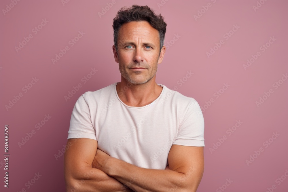 Portrait of a grinning man in his 30s with arms crossed on pastel or soft colors background Portrait of a grinning man in his 30s with arms crossed on pastel or soft colors background