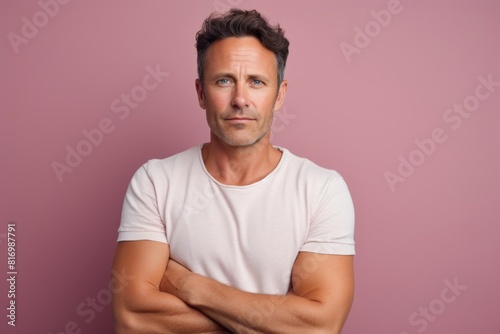 Portrait of a grinning man in his 30s with arms crossed on pastel or soft colors background