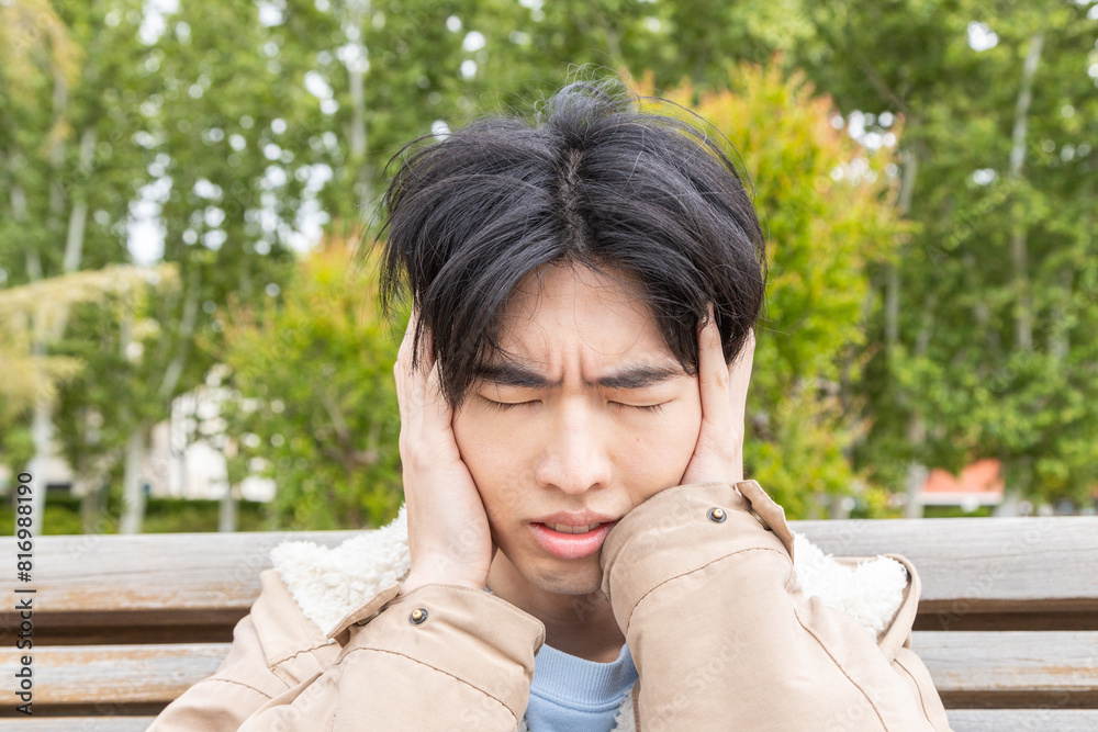 Young man experiencing headache symptoms outdoors Young man experiencing headache symptoms outdoors