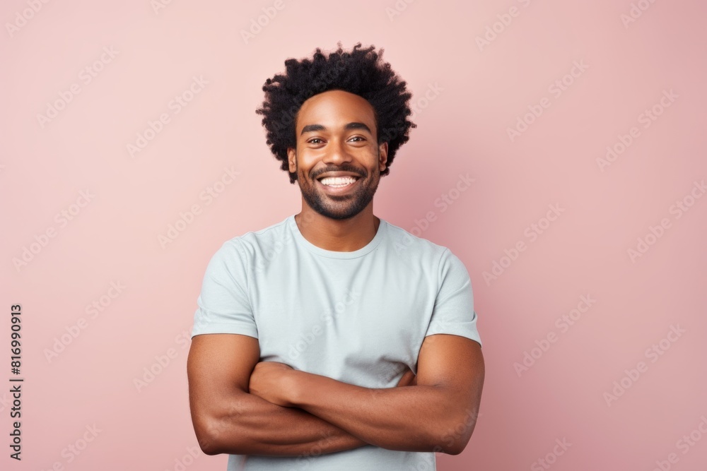 Portrait of a smiling afro-american man in his 30s with arms crossed on pastel or soft colors background Portrait of a smiling afro-american man in his 30s with arms crossed on pastel or soft colors background