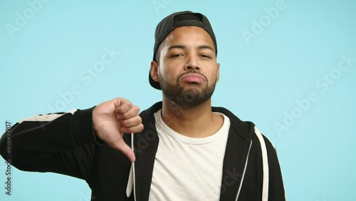 A man in casual wear expresses a stern warning with a cutthroat hand gesture followed by a thumbs-down sign, indicating disapproval or a significant loss. Camera 8K RAW. 