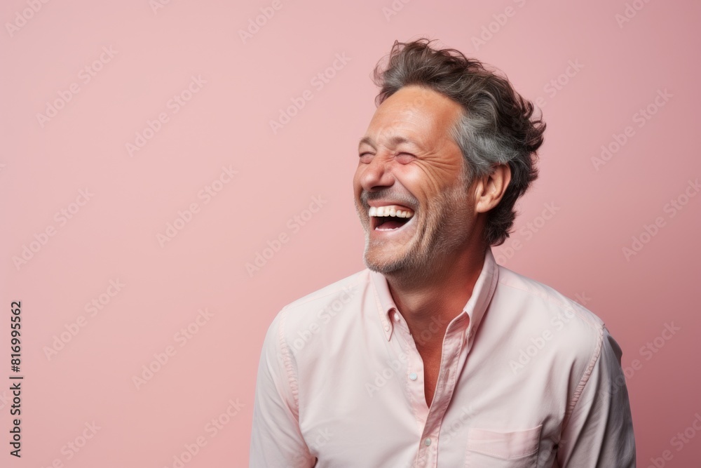 Portrait of a tender man in his 40s laughing in front of pastel or soft colors background Portrait of a tender man in his 40s laughing in front of pastel or soft colors background