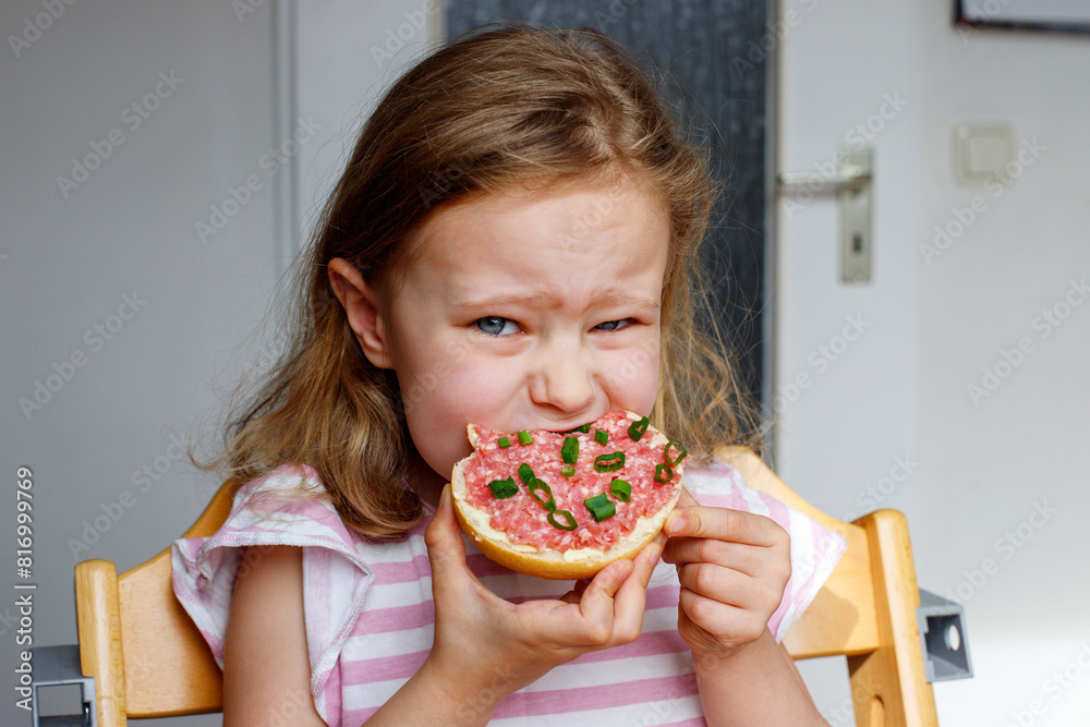 girl eats a meat sandwich in the kitchen. breakfast in Germany girl eats a meat sandwich in the kitchen. breakfast in Germany