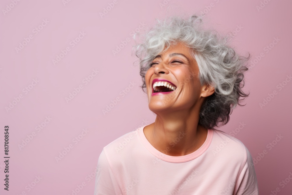 Portrait of a smiling woman in her 60s laughing on pastel or soft colors background Portrait of a smiling woman in her 60s laughing on pastel or soft colors background
