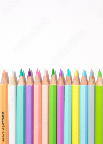 Pastel colored pencils in an even row on a white background

