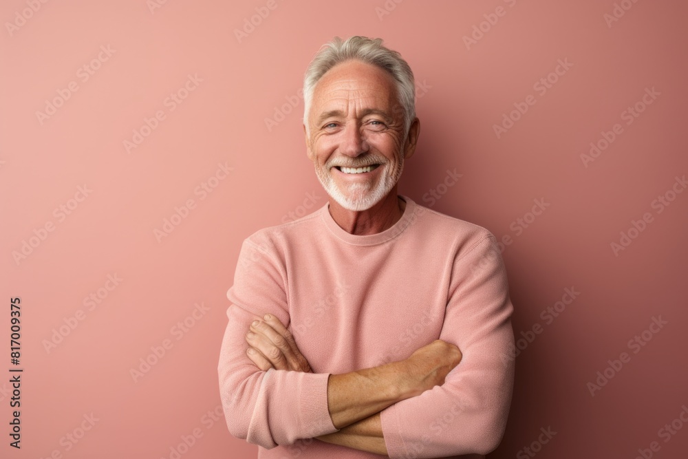 Portrait of a joyful man in his 60s with arms crossed in pastel or soft colors background Portrait of a joyful man in his 60s with arms crossed in pastel or soft colors background