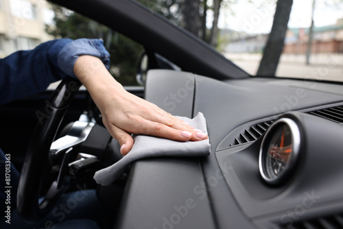Woman wiping her modern car with rag, closeup