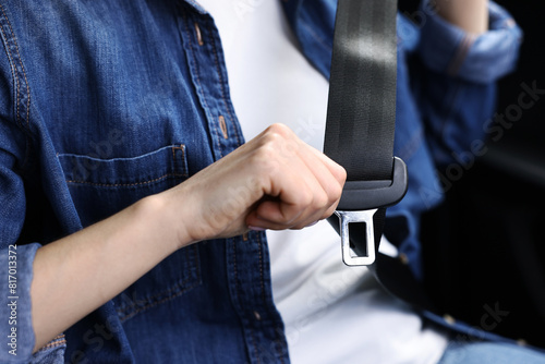 Woman fastening safety seat belt inside modern car