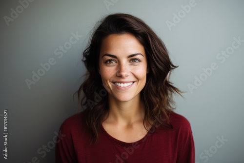 Portrait of a tender woman in her 30s smiling at the camera in minimalist or empty room background