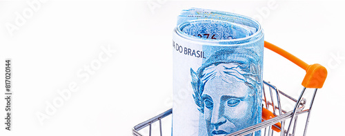 market cart with isolated white background, shopping basket, with large banknote of 100 reais from brazil inside. photo